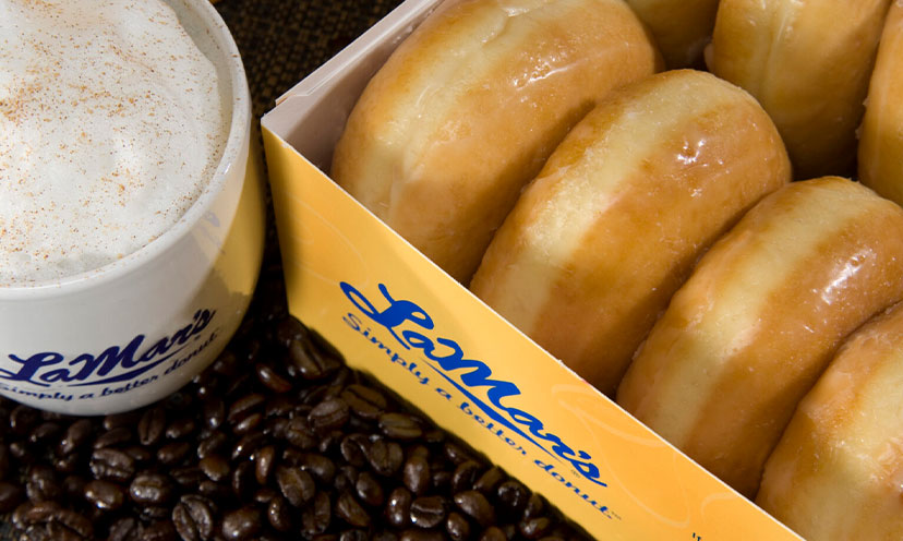 A La Mar's branded coffee cup and donut box with glazed donuts visible with coffee beans beneath