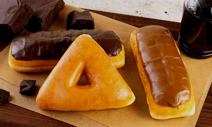 A chocolate bar donut, a maple bar donut, and a triangle shaped glazed donut on brown pieces of paper